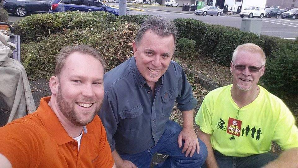 Guys smiling in front of yard debris
